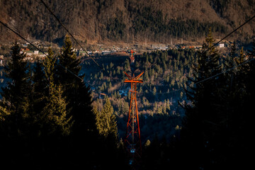 Panoramic view over the ski slope Poiana Brasov ski resort in Transylvania, Pine forest covered in snow on winter season,Mountain landscape in winter with the Bucegi Mountains in the background.