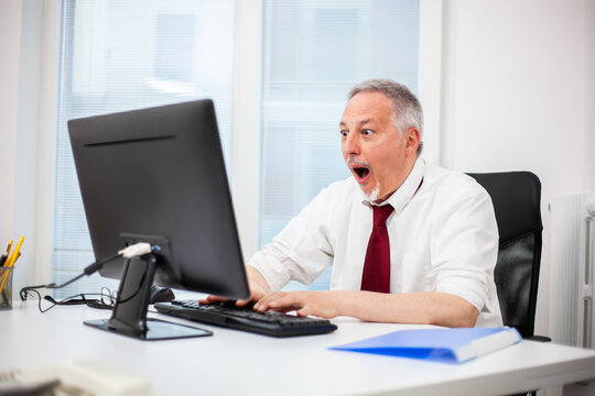Senior manager in a surprised expression in front of his pc monitor