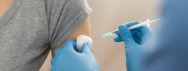 People getting a vaccination to prevent pandemic concept. Woman in medical face mask  receiving a...