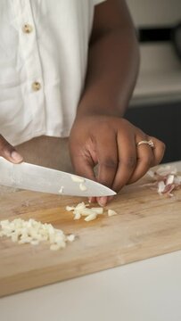 Close up of cuban woman hands cutting a raw garlic using a knife.