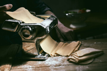 Crop chef using pasta machine for rolling dough