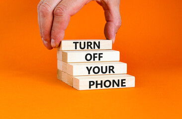 Turn off your phone symbol. Concept words Turn off your phone on wooden blocks. Beautiful orange background. Businessman hand. Business psychological turn off your phone concept. Copy space.