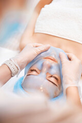 beautician removing mask from face of beautiful woman