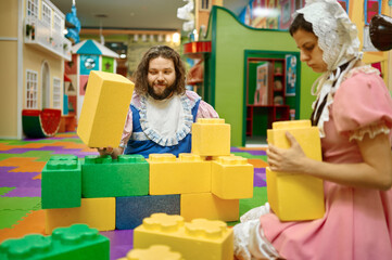 Funny man and woman like baby playing soft building blocks