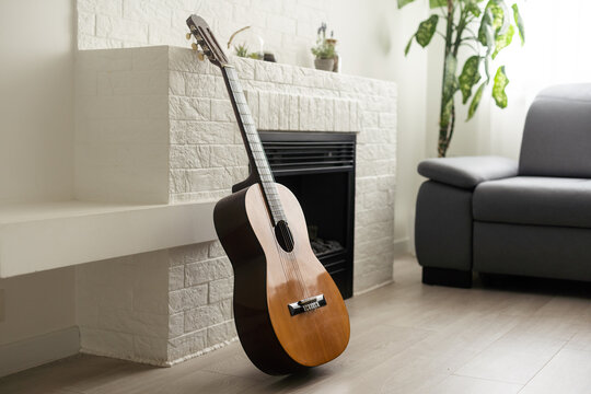 Minimalistic interior design concept. Acoustic guitar on grey textile sofa in spacious room of loft style apartment with wood textured laminated flooring. Background, copy space, close up