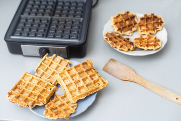 Modern waffle maker with ingredients on grey table.