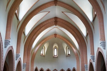 Cathedral interior corridor with classic arc design, windows with natural light, and place of worship architectural design.