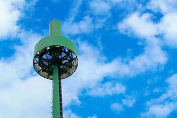 Isolated cell phone tower with blue sky background. Green painted cellular mobile transmitter.