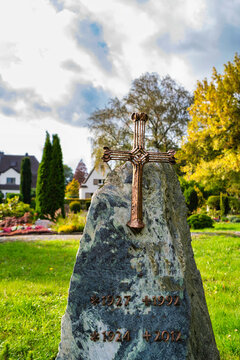 Schönes Bronzekreuz auf einem Stein auf einem Friedhof in Wülfrath