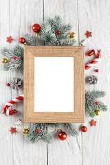 Fototapeta na wymiar Christmas photo frame with fir tree, red holiday decorations on white wooden background. Mock up. Flat lay. Top view