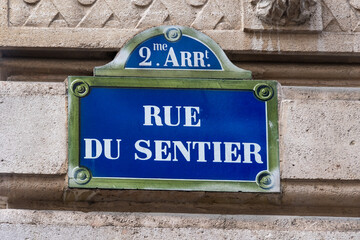 Plaque de rue parisienne traditionnelle sur laquelle est écrit "Rue du Sentier", située dans le quartier spécialisé dans l'industrie textile, dans le deuxième arrondissement de Paris, France