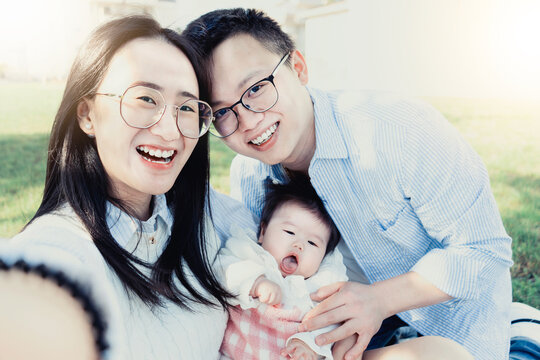 Happy ansian family taking selfie shot smiling at camera-Laughing young chinese people having fun with her small child at park- cheerful Couple with her  baby son . Love Concept.-Interracial  guys 
