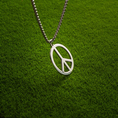 Metal medallion, with a pendant in the form of a symbol of peace on a green grass.
