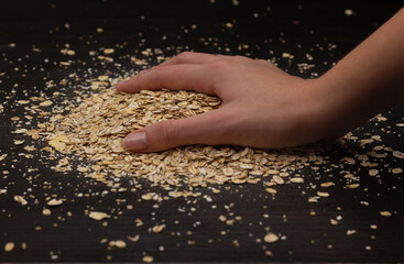 Female hands pouring muesli on a black background