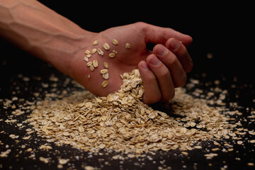 Male hands pouring muesli on a black background