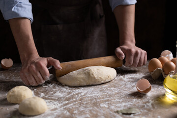 Baker chef man kneading dough bread and bakery ingredients for homemade cooking at table