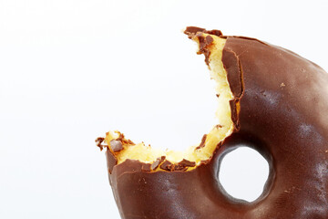 A bitten chocolate doughnut on a white background