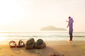 Father and daughter take off their sandals and lay on the beach. Daughter rides father's neck for a morning walk.