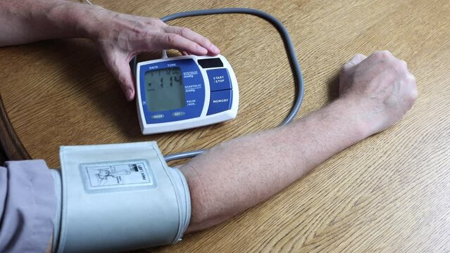 Using an electronic blood pressure monitor, Man in his 50s taking blood pressure at brachial artery to himself. 