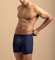 Cropped shot of muscular young man wearing underwear isolated on white background. 