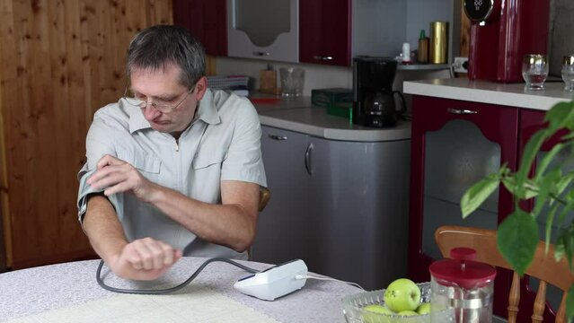 Measuring blood pressure with an electronic tonometer or pulsometer, middle aged Caucasian man independently measures blood pressure on brachial artery.