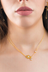 Young woman wearing a golden necklace and golden earrings. Beautiful valentine's gift.