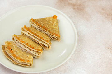 Christmas and New year tree shaped pancakes or crepes with red caviar decorations on light colored background. Holiday homemade food. Flat lay top view. Christmas food for children and kids.