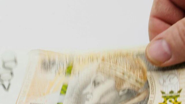 Polish money Zloty. Recalculation of money. Isolated. The hand counts money paper bills one hundred two hundred zloty. Polish banknotes fall on the table on a white background. Close-up.