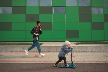 Mother and son having fun. Happy family mother teaches child son to ride a scooter. Support childhood parenthood idea. happy family concept. - 540543984