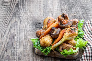 Oven roasted vegetables with spices and herbs on wooden board