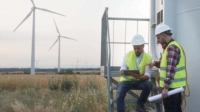 Team of technician and engineer working in wind turbine farm, planing renewable energy ecology project