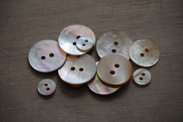 Buttons made of natural mother of pearl on a background of rough wooden texture.