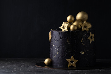 Luxury cake with dark blue cream cheese frosting decorated with golden chocolate stars and spheres....