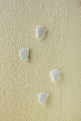Traces of a newborn baby made of edible confectionery mastic on the cake with white velvet cream coating. Textured background. Macro shot