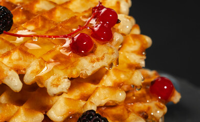 Fresh crispy Belgian waffles with fresh blueberries blackberries and red currants poured with fresh honey close-up