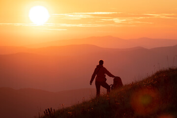 Hiker girl with heavy backpack looking at the sunset high in the mountains.