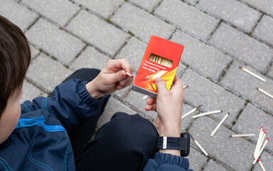 A little boy enthusiastically plays with matches, danger, children with matches, burning matches, a child lights a match, games with fire