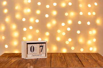 christmas, wooden calendar january 7 on wooden background and lights background