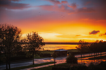 Pegwell Bay during sunset after a rain storm. The sea and roads are golden as they reflect the...