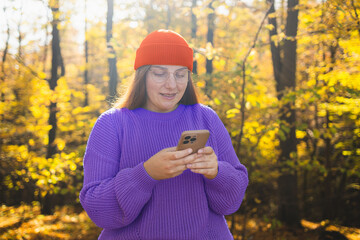 Beautiful happy woman in the autumn season.The woman is chatting on her mobile phone in warm clothes