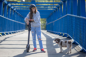 woman with electric scooter and dog walking over a bridge © aerogondo