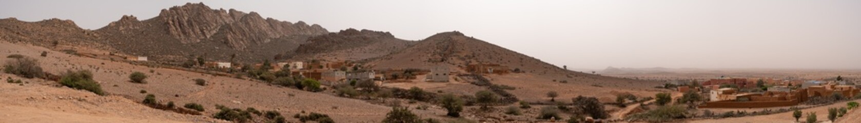 Amazing huge panorama landscape of lonely remote village surrounded by mountains, trees and sand in...