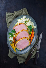 Gebackenes Kasseler Schweinesteak im Teigmantel mit Wirsing Kohl und Baby Karotten serviert als...