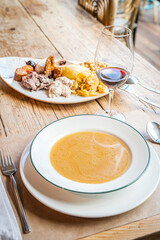 Cocido Madrileño, a traditional Spanish meal, served with soup, chickpeas, bacon, chorizo, black pudding, ham bone, boiled potato, cabbage, bread and a glass of red wine.