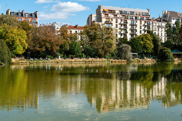 Fototapeta na wymiar Lake of Parc Montsouris in Paris with Birds and reflection of buildings. Shot on a sunny day at early autumn - Paris, France