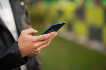 Closeup image of male hands with smartphone, searching internet or social networks, blurred background