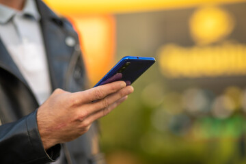 Unrecognizable man holding mobile phone in hand, blurred background