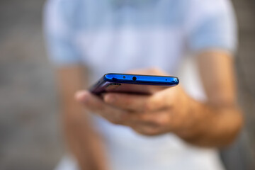 Closeup shot of an unrecognizable man holding mobile phone in hand, blurred background