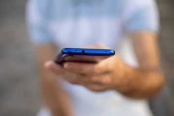 Closeup image of male hands with smartphone, searching internet or social networks, blurred background