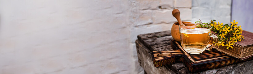 St. John's wort. Hypericum plants yellow flower on a wooden table next to an old recipe book. Mortar for the preparation of drinks from medicinal herbs.